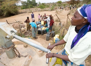 Eine Frau pumpt an einer Wasserpumpe