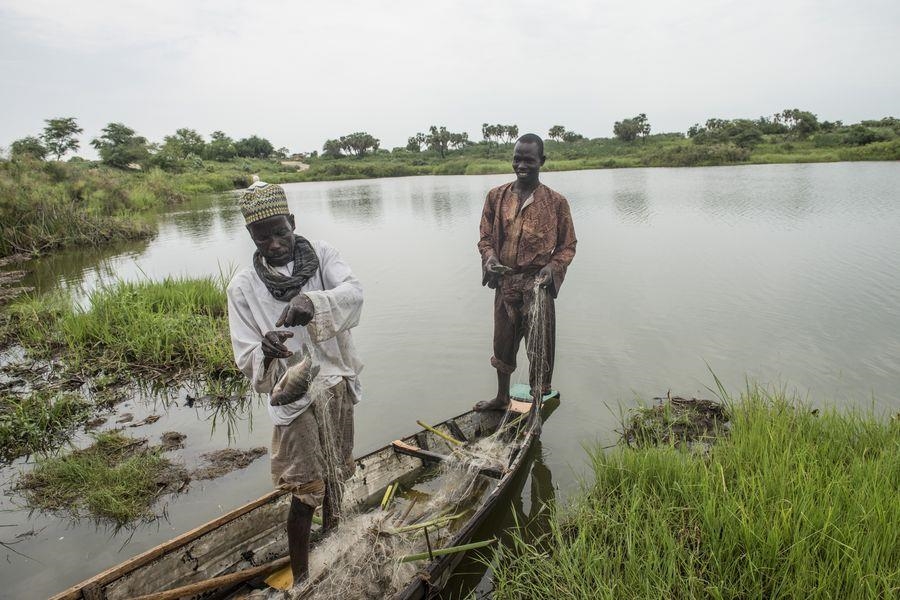 Zwei Männer stehen in einem Boot mit Netzen und Fischen (Michael Stulman, CRS)
