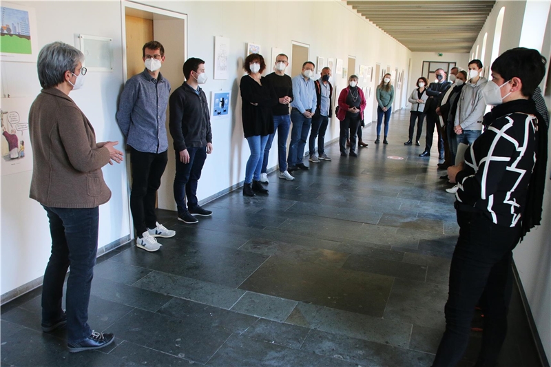 Das Foto zeigt eine Gruppe von Menschen, die locker in einem weiteren Flur zusammenstehen.