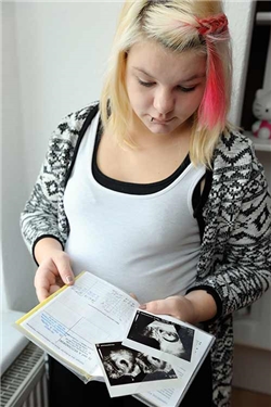 Junge Schwangere betrachtet ihren Mutterpass / DCV/ Margit Wild