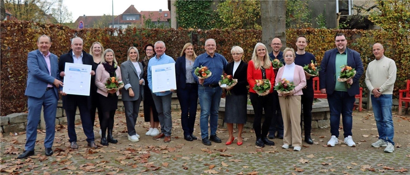 eine Gruppe von Personen steht nebeneinander und hält Zertifizierungsurkunden in den Händen