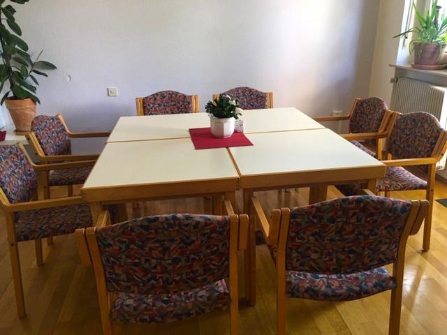 Gemeinschaftsraum mit Sitzgruppe für 8 Personen um einen quadratischen Tisch (Caritasverband Darmstadt e. V.)