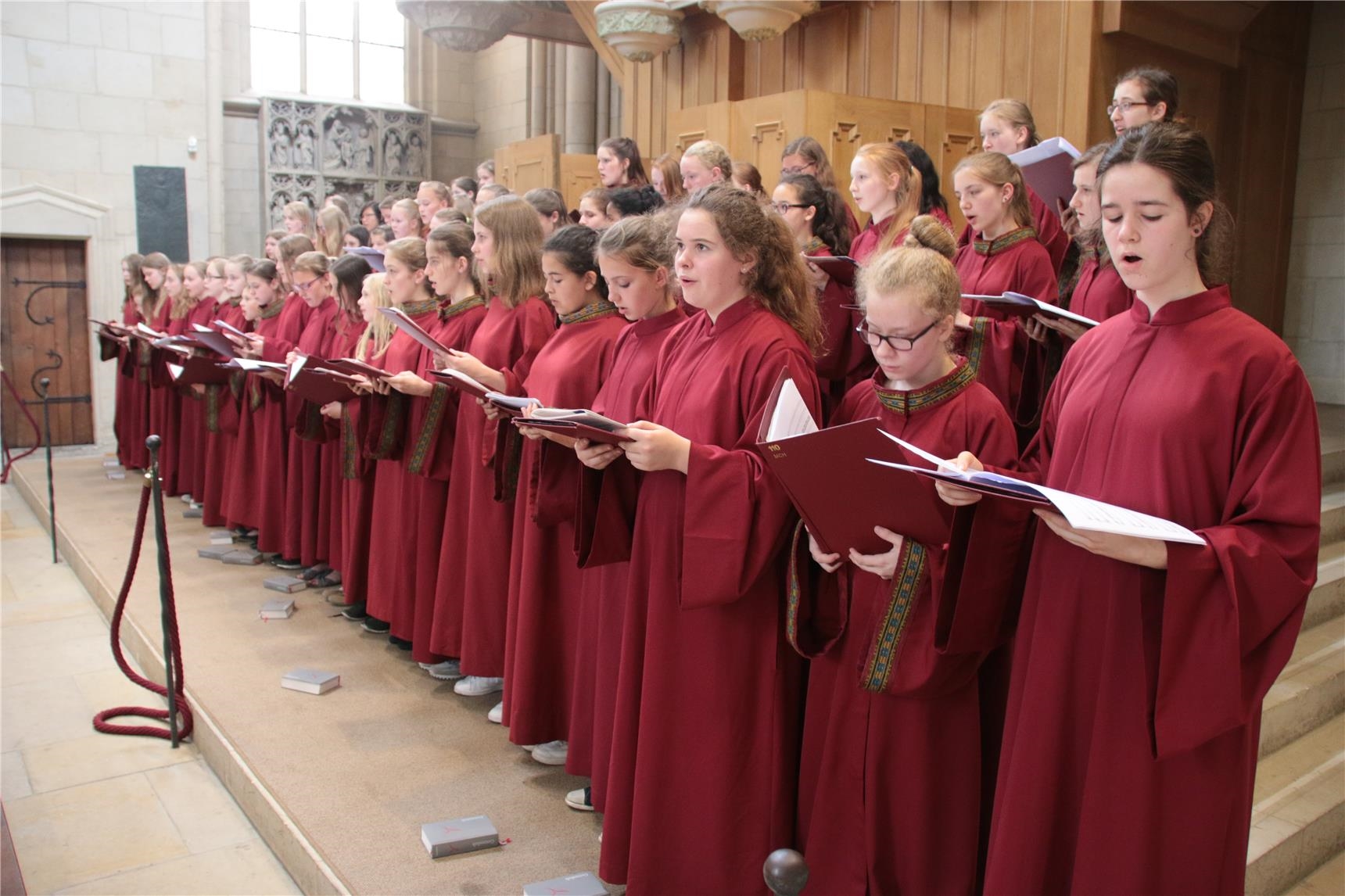 Das Foto zeigt einen großen Chor junger Schüler, die rot gewandet sind, vor einer Orgel (Harald Westbeld)