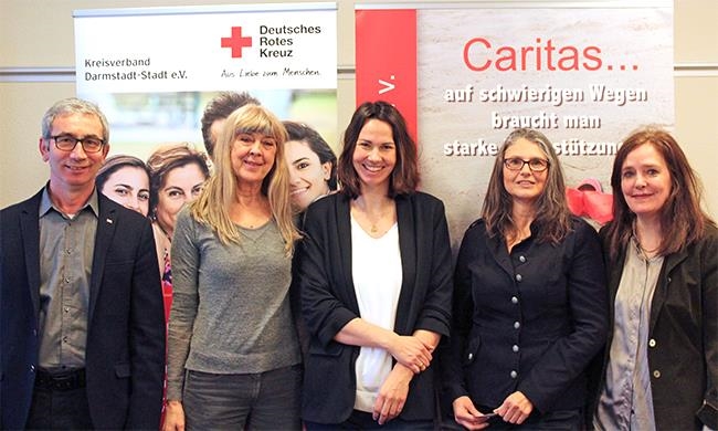 Gruppenfoto, vier Frauen und ein Mann, vor Bannern mit Logos von DRK und Caritas (Caritasverband Darmstadt e. V.)