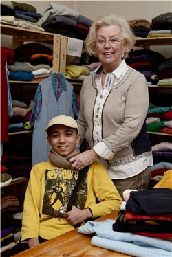 Eine Ehrenamtliche umarmt einen Jungen, der gerade neue Sachen in der Kleiderkammer erhalten hat / Caritas Bistum Essen / C. Grätz