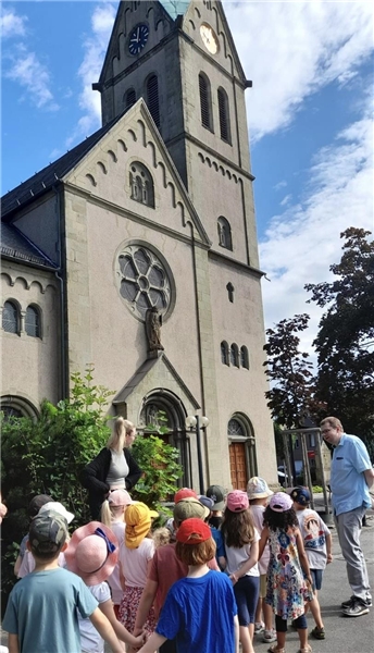 Vorschulkinder stehen zusammen vor einer Kirche.