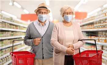 Ein Rentnerpaar mit Mund-Nase-Schutz in einem Lebensmittel-Supermarkt.